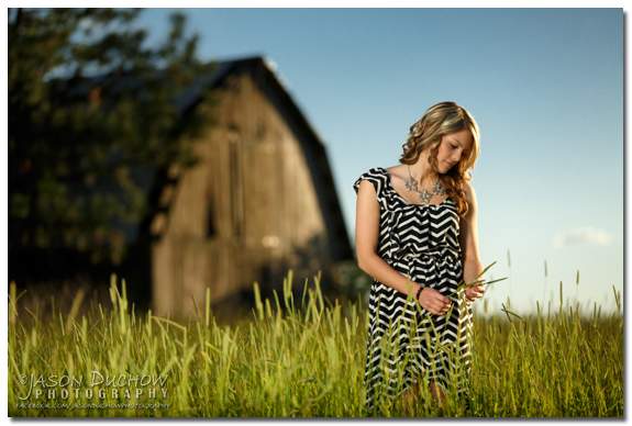 senior portrait in a field with an old barn