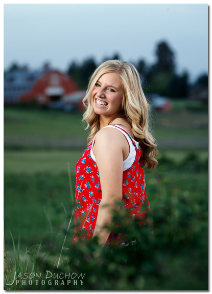 senior portrait with a barn in the distance