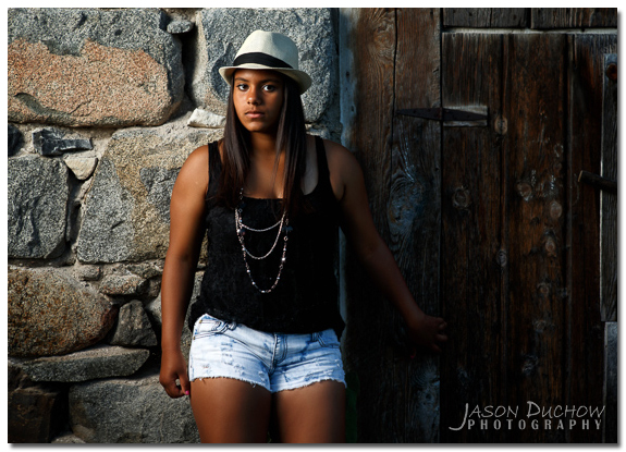 senior portrait with dramatic light along a rock wall